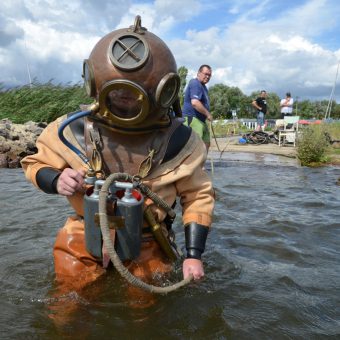 Keine leichte Angelegenheit im 90-Kilo-Anzug: Helmtaucher auf dem Weg ins Wasser