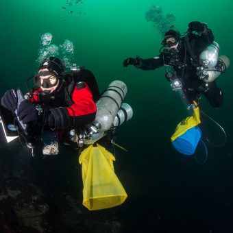 Die mit Ausrüstung und Fanggerät schwer bepackten Ozeaneum-Taucher Henning May und Alexander Dressel.