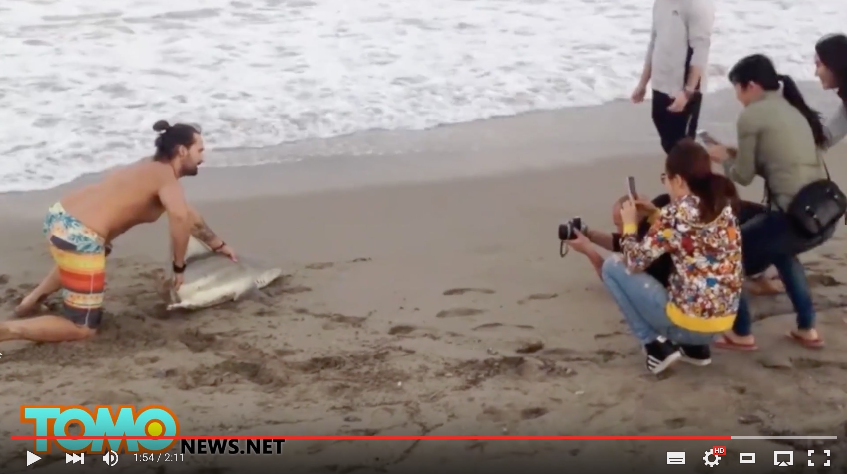 Selfie-Wahn: Der Beach Boy am Strand von Florida lässt sich von Passanten mit Smartphones fotografieren. Foto: youtube.com