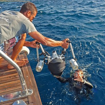 Anreichen lassen: Die Unterwasserkamera sollte man sich vom Schiff mit Domeportschutz anreichen lassen. Die Abdeckung kann man während des Tauchgangs ins Jacket stecken.