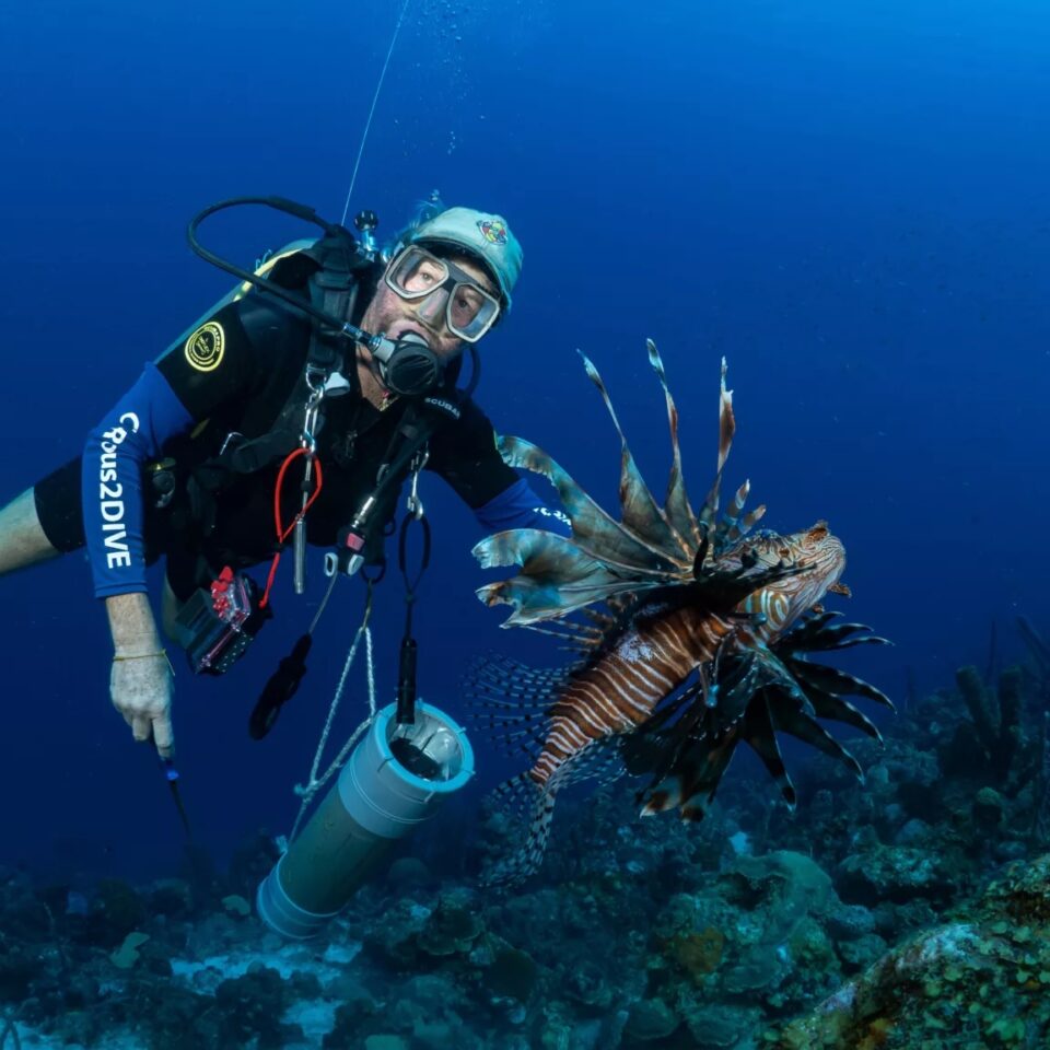 Taucher mit frisch erlegtem Feuerfisch während eines Tauchgangs auf Curaçao