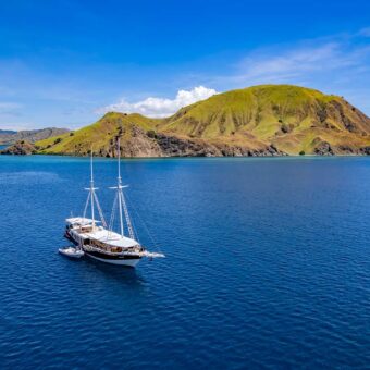 Tauchsafarischiff im Komodo-Nationalpark vor grüner Vulkaninsel