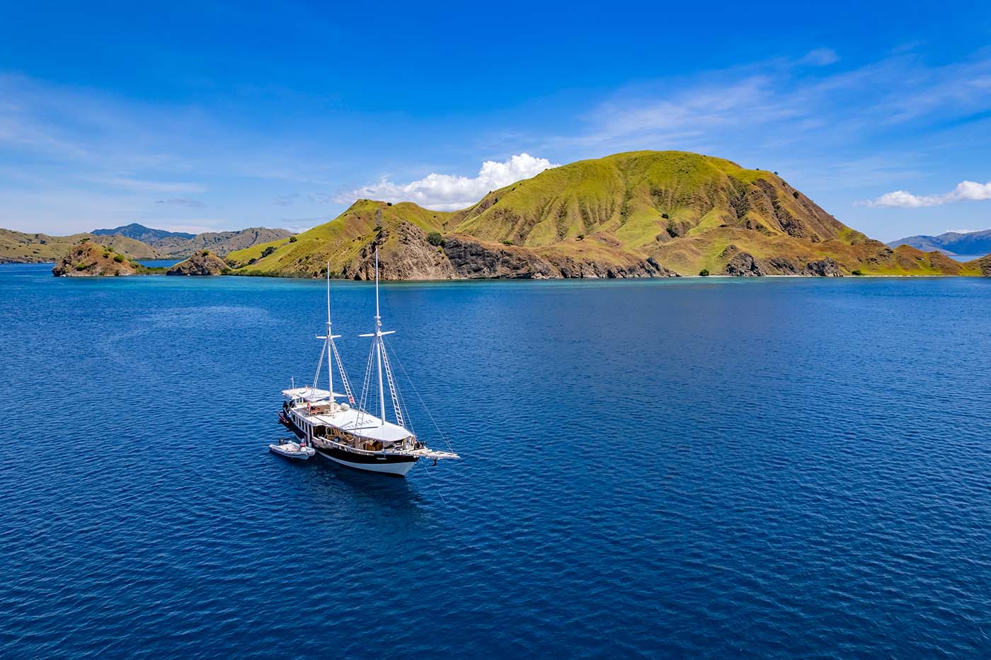 Tauchsafarischiff im Komodo-Nationalpark vor grüner Vulkaninsel