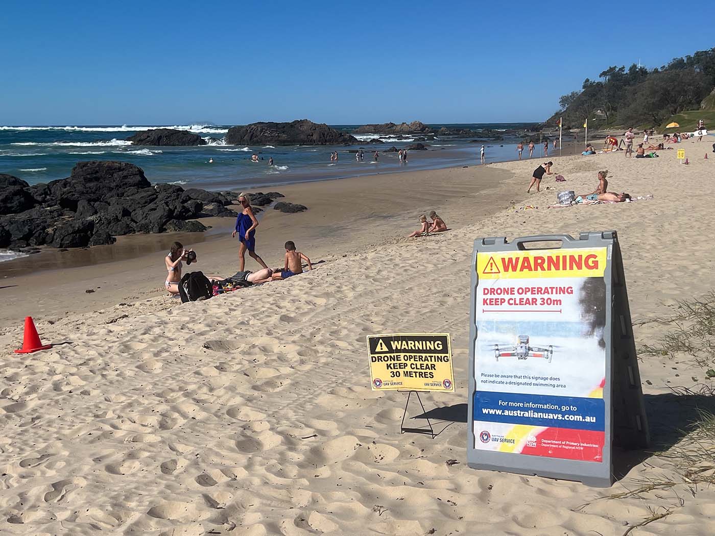Warnschilder informieren am Strand von Sydney über die Drohnenüberwachung zur Erkennung von Haien.