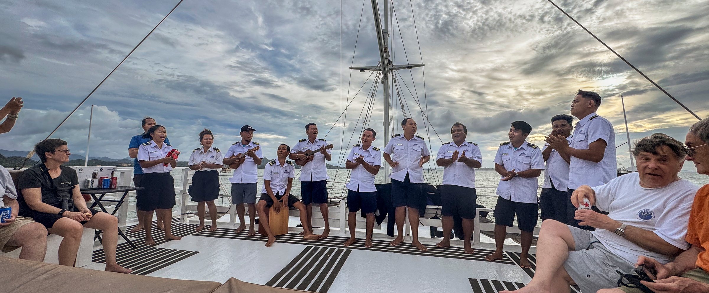 Die Crew der Komodo Aggressor steht in weißen Uniformen an Deck und verabschiedet die Gäste