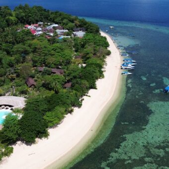 Luftaufnahme der Koralleninsel Siladen mit Strand, Siladen Resort & Spa und Riff im Bunaken-Nationalpark