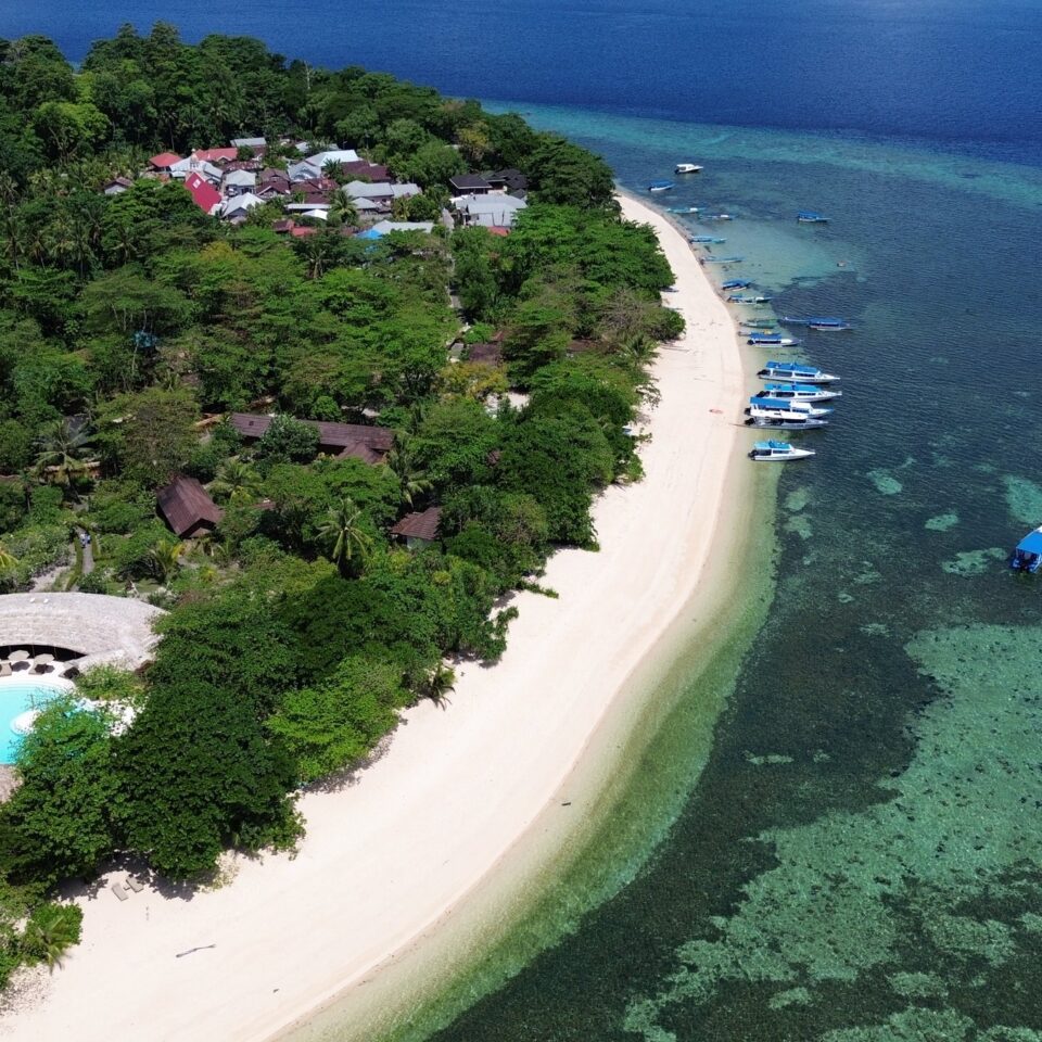 Luftaufnahme der Koralleninsel Siladen mit Strand, Siladen Resort & Spa und Riff im Bunaken-Nationalpark